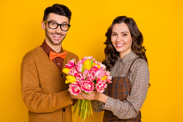 Photo of charming couple anniversary gift bouquet tulips smile isolated on shine yellow color background