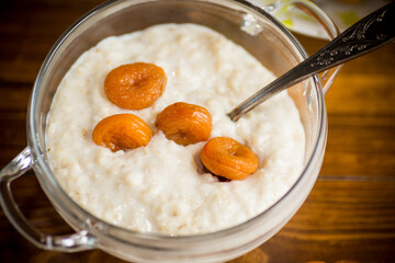 cooked boiled sweet oatmeal with dried apricots in a bowl