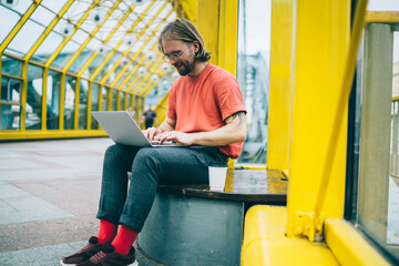 Fototapeta na wymiar Happy guy browsing laptop in pedestrian bridge