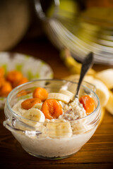cooked boiled sweet oatmeal with with dried apricots and bananas in a bowl