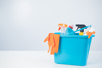 Blue bucket with cleaning products and rubber gloves for homework on a white background