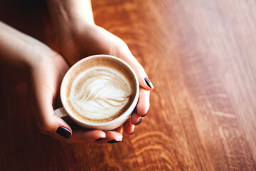 Woman hands holding mug of hot drink that standing on wooden table