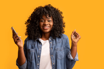 Excited black woman with smartphone raising hands up