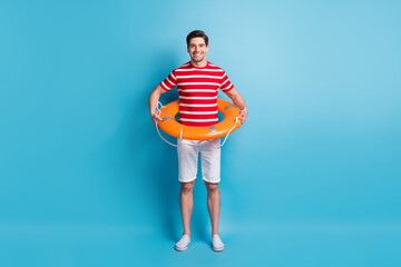 Full length body photo man wearing orange circle ready to swim in ocean isolated on vivid blue color background