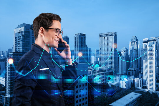 Handsome eastern analyst pensively processing conference call by phone to find financial solution for venture capital project. Hologram chart over Bangkok city background