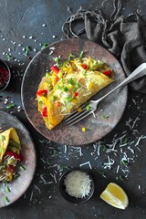 Healthy breakfast food: stuffed omelette with vegetables on dark background. Top view with copy space.