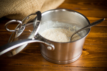 sweet boiled oatmeal in a saucepan with a spoon