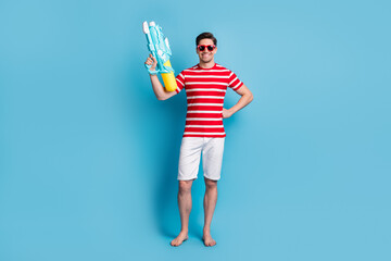 Full length photo of positive cool man hold water gun play game summer time isolated on blue color background
