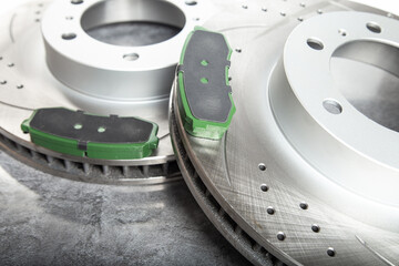 brake pads and perforated brake discs on a stone gray table