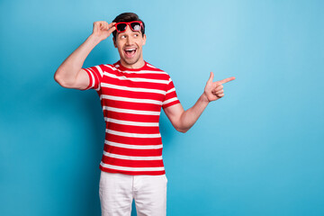 Photo portrait of cheerful curious man wearing sunglass pointing advertising blank space isolated...