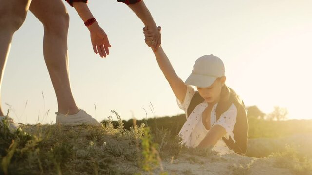 Teamwork helping hand. Family team tourists lends helping hand on climb cliffs mountains. Mom and daughter strive for victory by lending a helping hand. Business and travel silhouette concept.