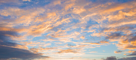 Naklejka na ściany i meble Beautiful sky painted by the sun leaving bright golden shades.Dense clouds in twilight sky in winter evening.Image of cloud sky on evening time.Evening sky scene with golden light from the setting sun