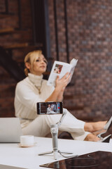 The concept of blogging and vlogging is a young woman blogger recording poetry on the camera. Soft selective focus, defocus, art noise.