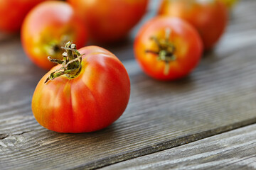 Fresh tomatoes on wooden table over bokeh background
