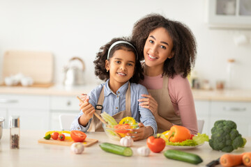 African american mother and daughter cooking tasty salad