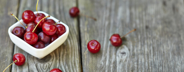Cherry in a bowl on grey wooden old table. Ripe ripe cherries. Sweet red cherries. Free space on table