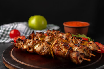 Chicken skewers with apples and vegetables on a black background
