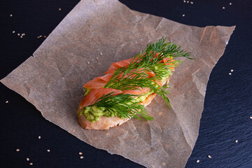 a slice of crispy baguette anointed with avocado and garnished with smoked salmon fillet and fresh...