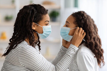 Side view of woman putting face mask on her daughter
