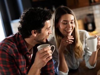 Loving couple drinking coffe in the kitchen. Happy smiling wife enjoy in the morning with her husband.