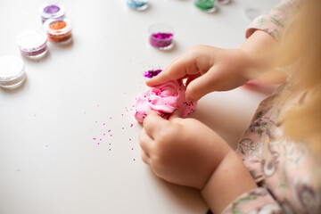 the hands of a little girl, a child who plays with plasticine and jars of sparkles. Child development, fine motor skills, hobbies, classes and home education. High quality photo