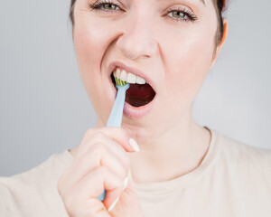 Close-up portrait of caucasian woman brushing her teeth. The girl performs the morning oral hygiene...