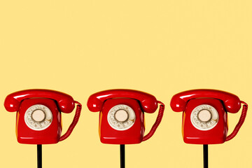 red rotary dial telephones on a yellow background