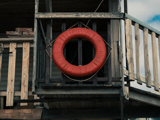 Old retro red lifebuoy hanging on wooden balcony. Help, rescue concept. Marine wallpaper copy...