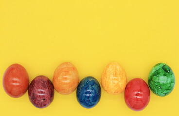 easter eggs in a row on a yellow background, top view copy space