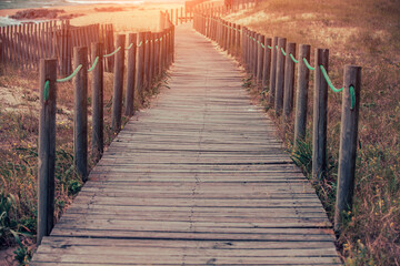 Wooden walkway on the sandy seashore in the magical light of the sunset. Beautiful seascape in the evening. Porto, Portugal