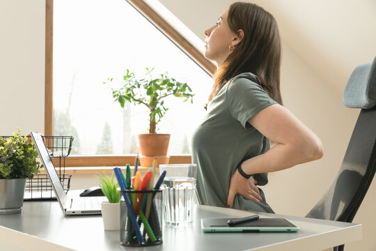 Working from home and exercise at home office. Beautiful woman stretching her back while sitting at workplace. Healthy living and body care.