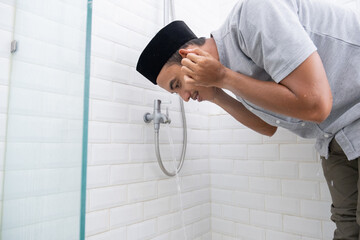 portrait of young Muslim man perform ablution (wudhu) before prayer at home