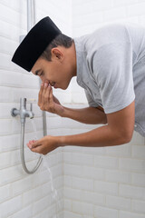 portrait of young Muslim man perform ablution (wudhu) before prayer at home