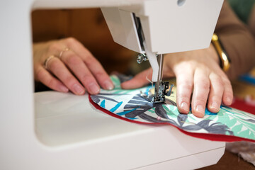 hands of a female seamstress while working on a sewing machine close-up