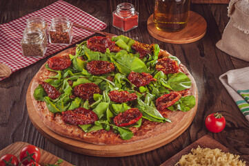 Brazilian pizza with tomato sauce, mozzarella, argula, dried tomatoes and oregano (Pizza de rucula com tomate seco)