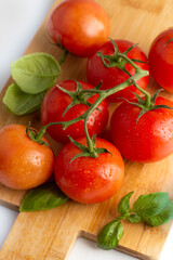 Blurred image of a sprig with tomatoes and basil leaves on a cutting board.