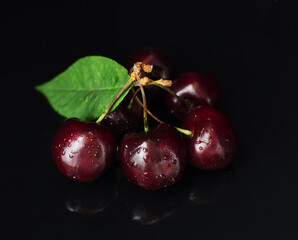Cherry berries on a black mirror background. Fresh ripe berries, healthy food