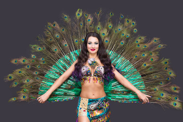 Dancer holds peacock feathers in her hands, black background.