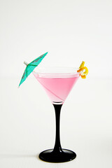 cosmopolitan cocktail in martini glass with lemon peel and green umbrella