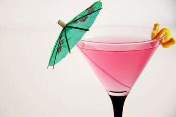 cosmopolitan cocktail in martini glass with lemon peel and green umbrella