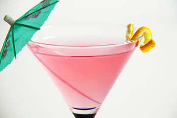 cosmopolitan cocktail in martini glass with lemon peel and green umbrella