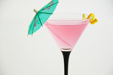 cosmopolitan cocktail in martini glass with lemon peel and green umbrella