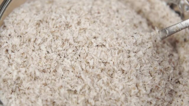 Stirring psyllium husks with a spoon close-up in a cup. Macro shot. Slow motion. Food herbal supplement for cleansing and healing