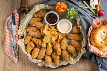 Breaded fried chicken wings with potato chips sauces and vegetables