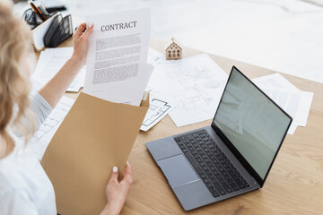 Businesswoman sitting in office, holding contract in hands