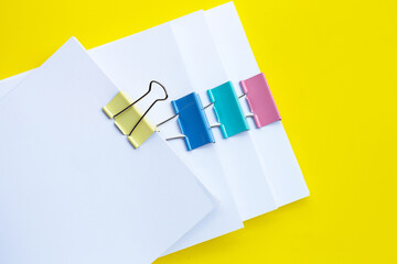 Stacking of business document with colorful binder clips on yellow background.