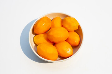 Peeled marian plum fruit on white.