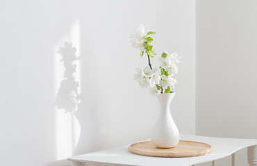white spring flowers in vase on vintage shelf