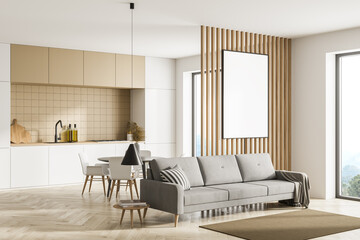 Modern kitchen interior, dining area and living room space with panoramic windows with countryside view. Furnished by beige sofa, table and chairs and one blank framed poster on wooden wall. Mock up.