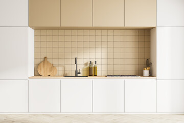 Front view of modern kitchen interior with kitchenware. Parquet floor. White facades and beige ceramic tiles on wall